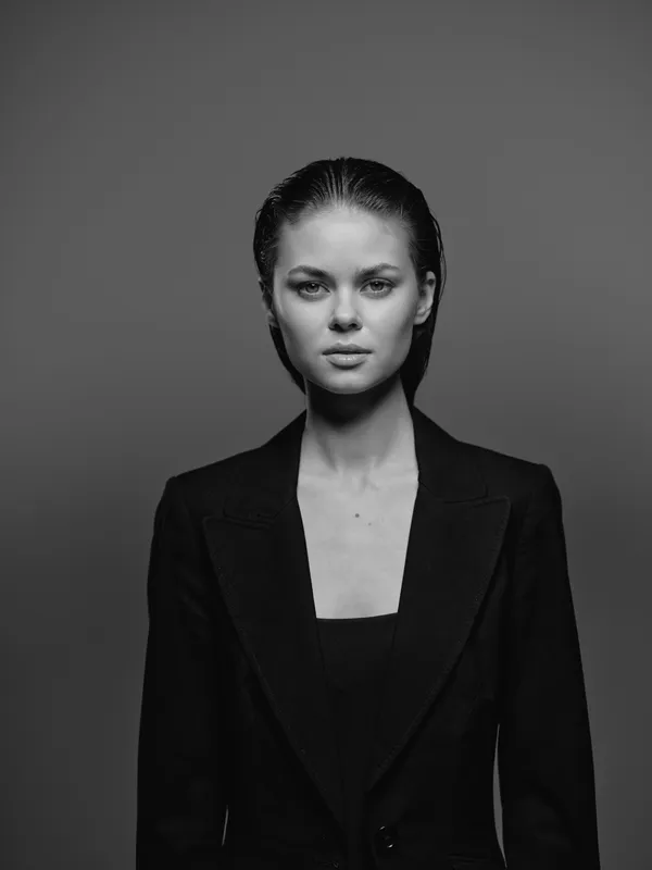 Black and white portrait of a serious woman wearing a black blazer with wet hair in a studio setting