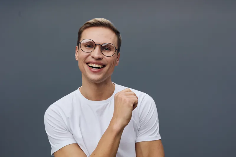 Smiling woman wearing glasses and a white t-shirt, joyful expression, casual look, indoor studio portrait with plain grey background, people lifestyle concept, positive mood
