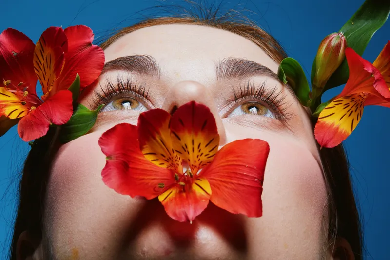 Close up portrait of a woman with flowers, capturing vibrant emotions and natural beauty against a blue background, perfect for wellness and self love concepts