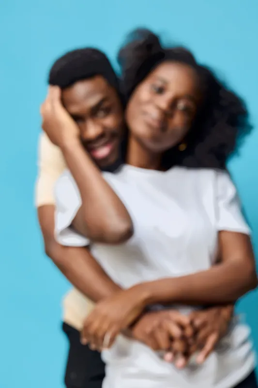 A joyful young African couple embracing in a playful moment against a vibrant blue background, showcasing love, happiness, and connection