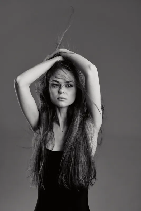 black and white portrait of a young woman with long hair wearing a black top expressing calmness and elegance