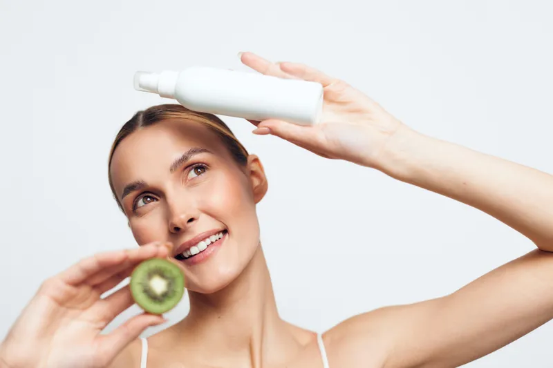 Smiling woman with jade roller applying face serum skincare massage, close up portrait on bright white background, facial treatment for wellness and self care