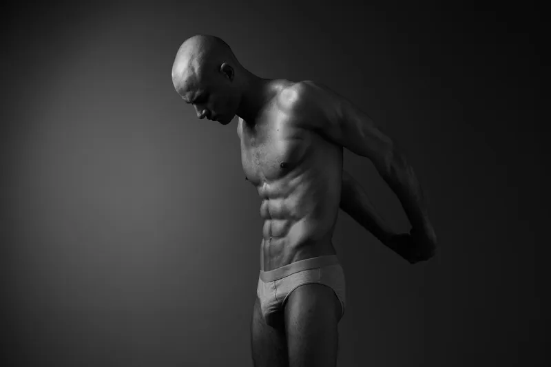 Black and white image of a focused man preparing for workout, showcasing his toned physique and determination for fitness and strength training.