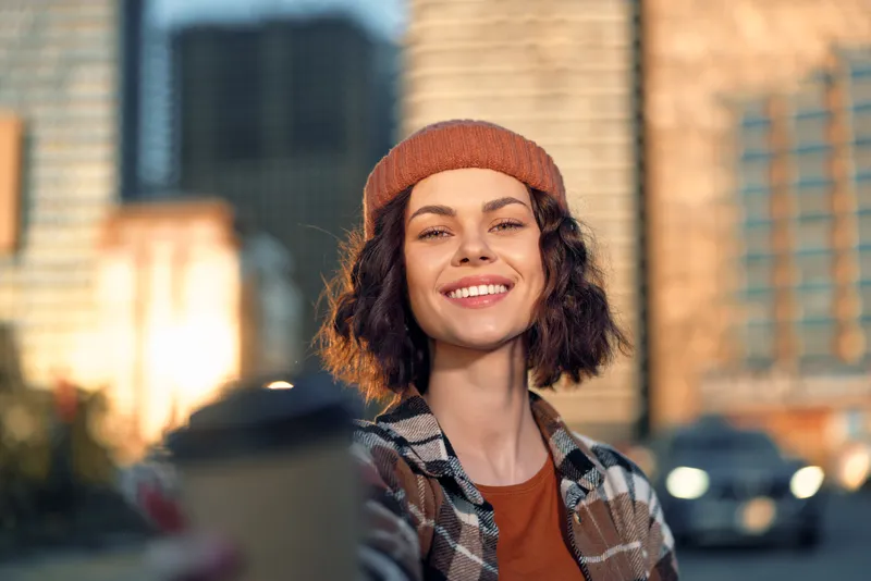 Woman smile coffee urban portrait, candid lifestyle capture at golden hour glow with authenticity and mindful living, emotional storytelling in a warm modern city scene.