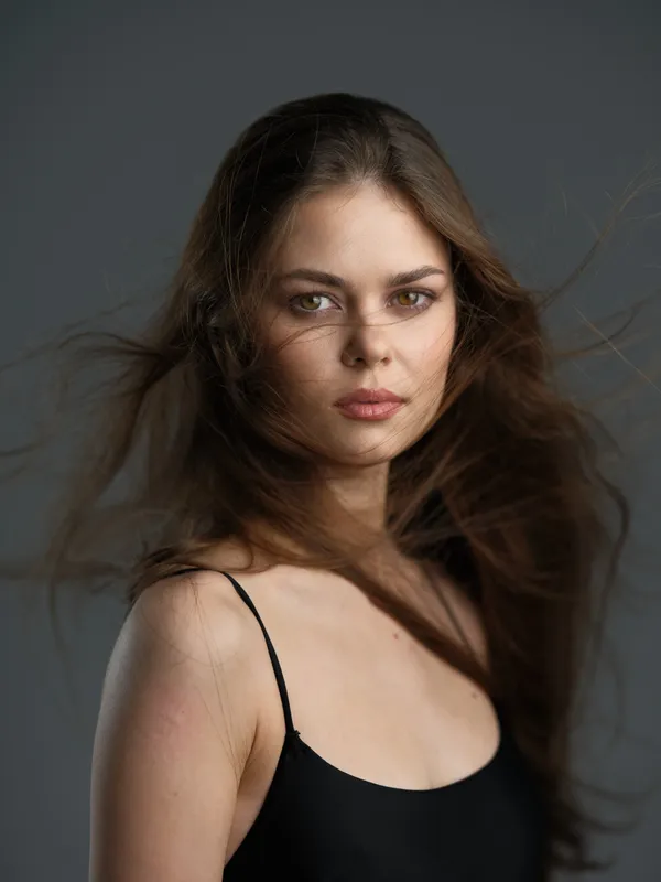 Portrait of a young woman with flowing hair wearing a black top, displaying a calm and confident expression.
