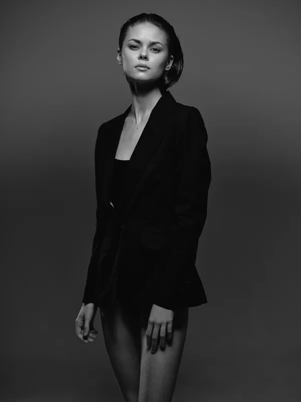 black and white portrait of a young woman wearing a dark blazer with a serious expression and minimalist style