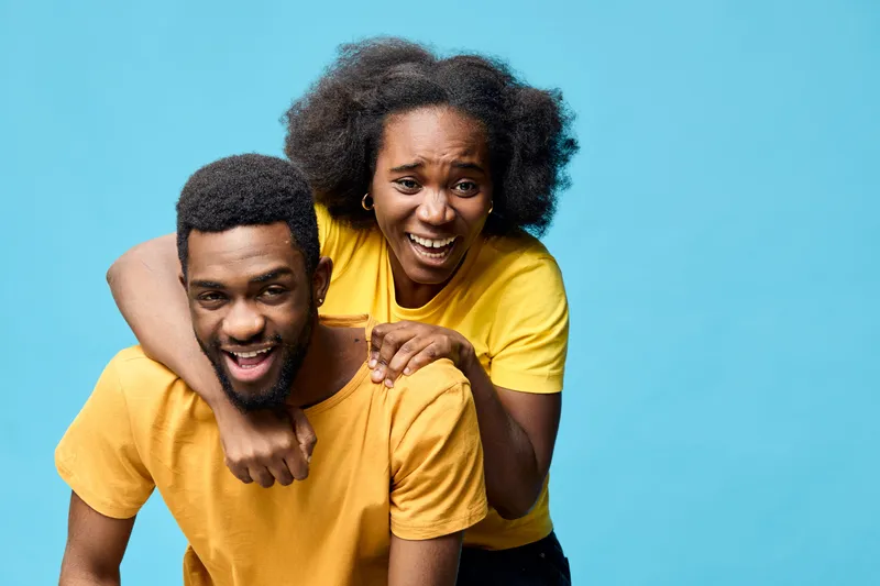 Happy African couple in yellow shirts against a blue background, showcasing joy and togetherness, perfect for lifestyle and relationship themes