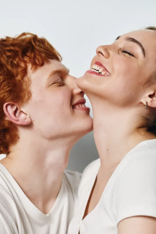 Couple, love and affection with happy young man and woman smiling closely in white casual shirts. Enjoyment, relationship and joy with intimacy and connection on light background.
