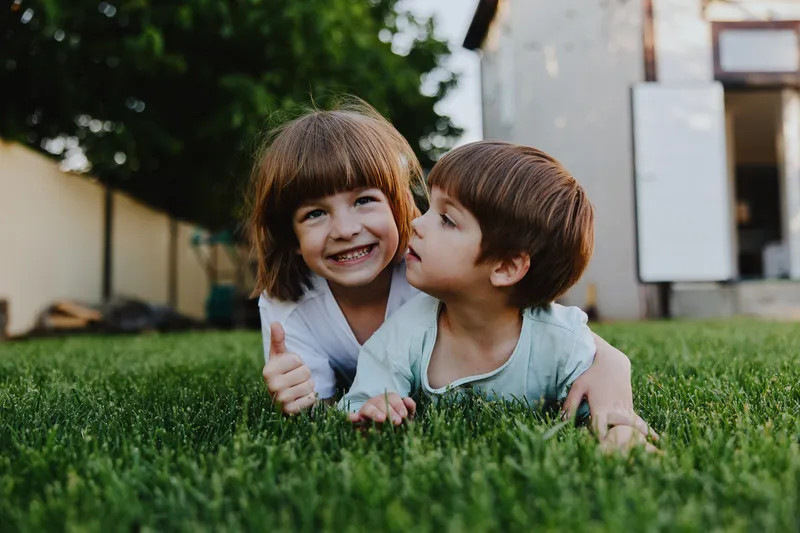 Happy children playing outdoors, enjoying a sunny day in a green garden, expressing joy and friendship in a natural setting.