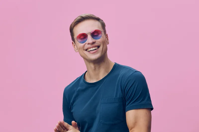 smiling man wear blue t-shirt and round colorful sunglasses isolated on pink background digital nomad freelance working concept