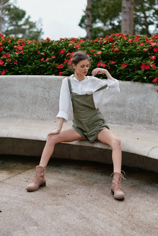 Fashionable young model in a stylish outfit posing in a floral park, showcasing casual summer style, confidence, and contemporary fashion aesthetics