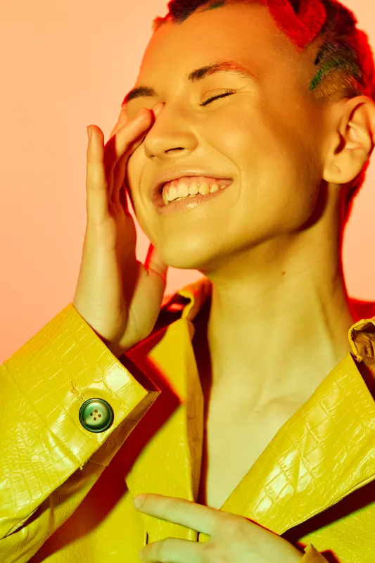 smiling woman with red braided hair wearing bright yellow jacket, expressive joyful face, warm lighting and vibrant fashion style portrait