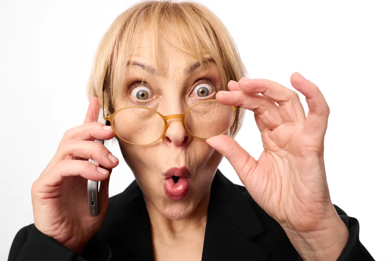 Woman surprised with glasses and phone call gesture, close up portrait in studio on white background. Communication concept, eyewear, surprise emotion.