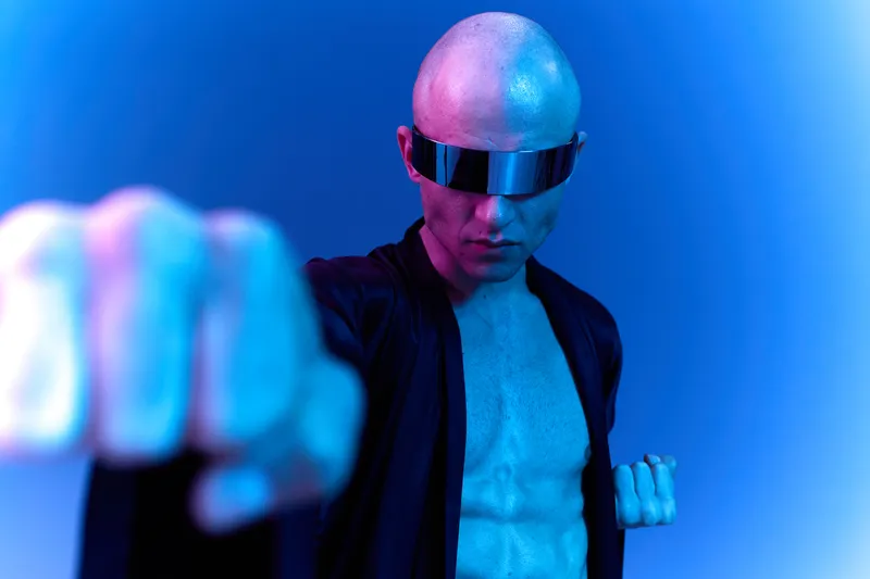 Futuristic man with a bold look, wearing trendy sunglasses and a striking outfit, captures a confident pose. Dynamic lighting enhances the visual appeal.