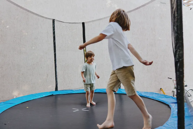 Happy children playing together on a trampoline, enjoying their time outdoors in a cheerful atmosphere, surrounded by nature and blissful moments.