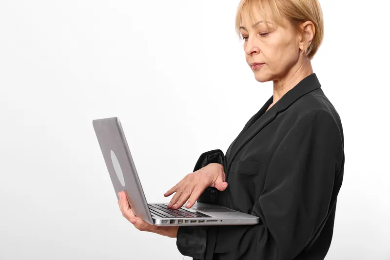Stressed woman at laptop in office looks tired, eyes down, hands on keyboard, concept for burnout, fatigue, mental health, work pressure