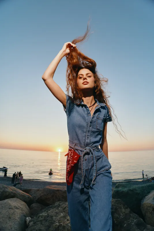 Modern boho-western denim street style woman poses confidently outdoors at sunset, showcasing lifestyle fashion with film color tones and relaxed summer vibes.