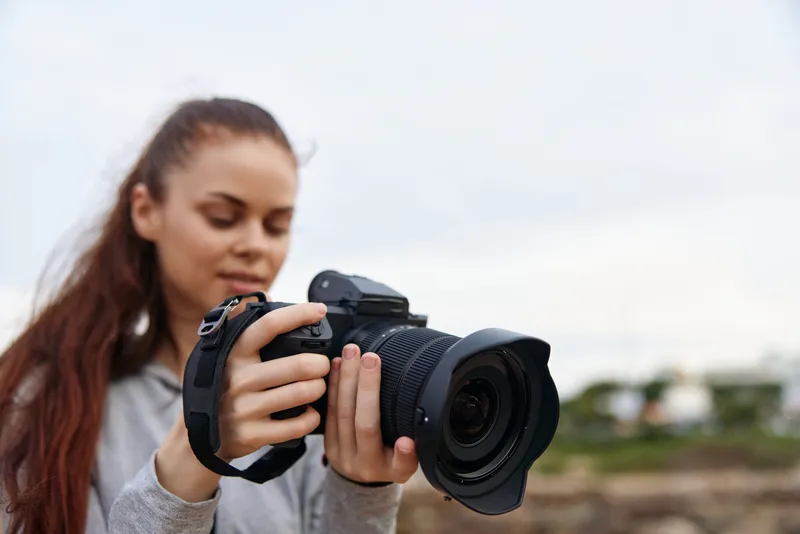 Young woman focused on capturing stunning photography with a DSLR camera outdoors in nature, showcasing a passion for creativity and exploration in photography