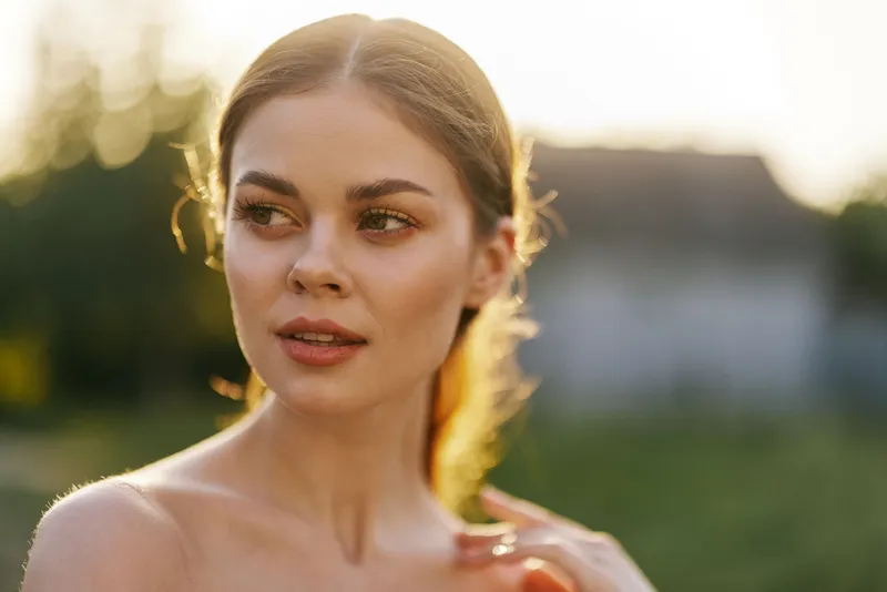 Portrait of a young woman with long hair in a natural setting, reflecting joy and serenity during golden hour, showcasing natural beauty and vibrant emotions