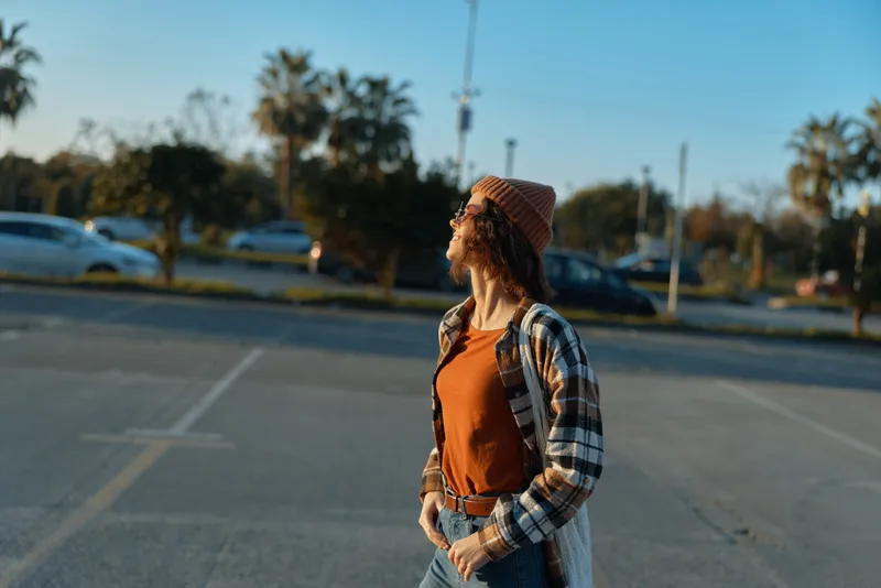 Woman candid portrait in an urban parking lot at golden hour, wearing beanie and flannel, capturing authenticity and mindful living with emotional storytelling and warm sunlight glow.