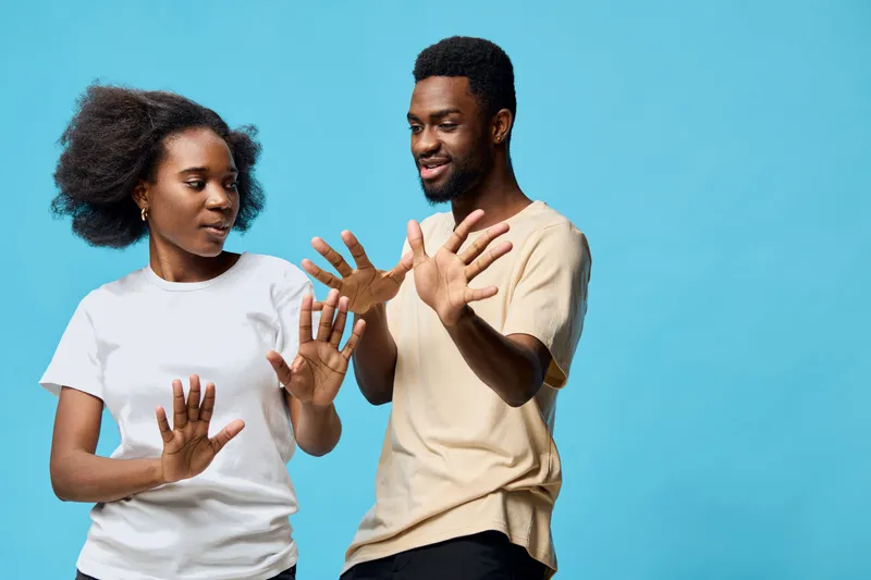A joyful Black couple engaging in playful interaction against a bright blue background, showcasing emotions of happiness and connection, perfect for relationship themes