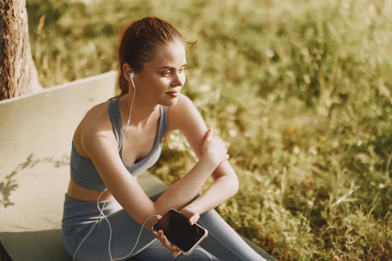 Young woman enjoying a moment of relaxation in activewear, listening to music outdoors, embodying a healthy lifestyle KEY relaxation, activewear, healthy lifestyle, outdoor, music, woman, nature, f