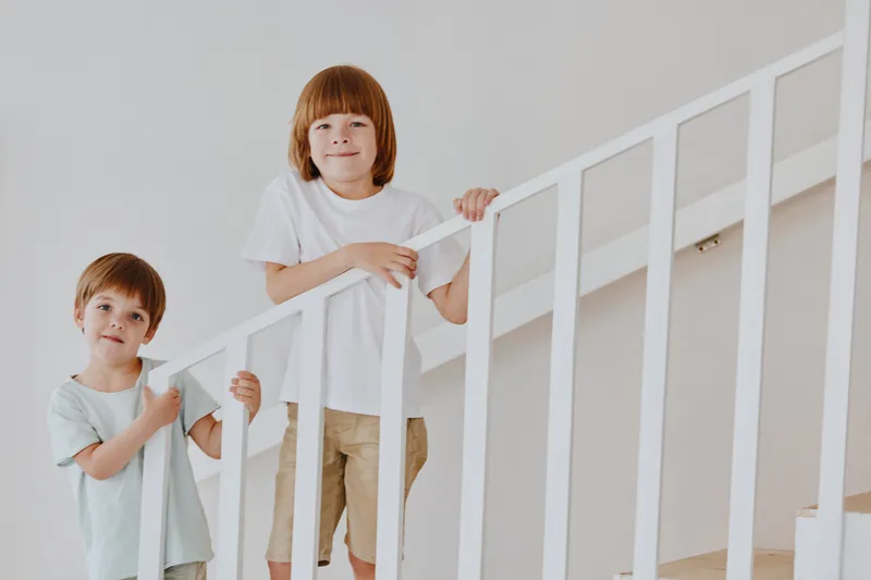 Two cheerful boys smiling on the staircase, showcasing a light and playful atmosphere perfect for family themes and childhood innocence.