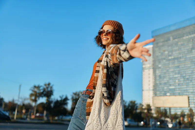 Woman portrait in city smiling and candid lifestyle moment with authenticity and golden hour glow, relaxed mindful living and emotional storytelling, warm sunlight and open arms.