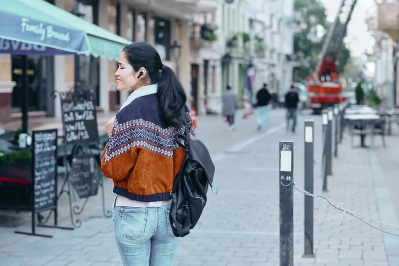 woman, backpack, street, cafe, urban, fashion, outdoor, jacket, sweater, sidewalk, a woman walks along a cafe street scene with a backpack, capturing urban style and casual travel vibe