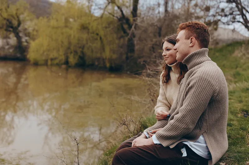 Couple romantic lake park sweater knitwear tranquility together embrace nature sit close by a calm lake on a park bench enjoying a peaceful lifestyle moment in soft evening light intimate connection