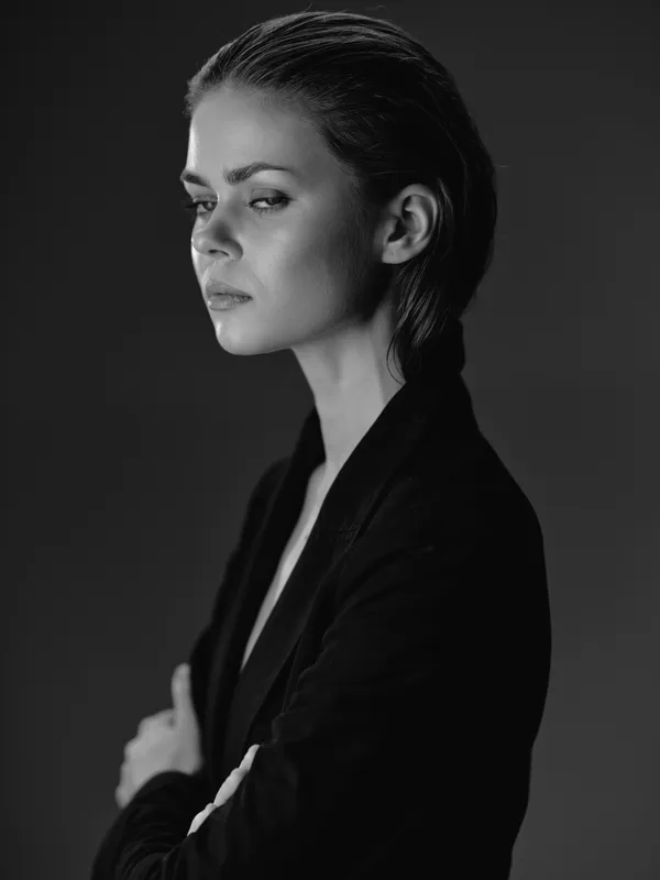 Black and white portrait of a serious young woman in a blazer with a contemplative expression.