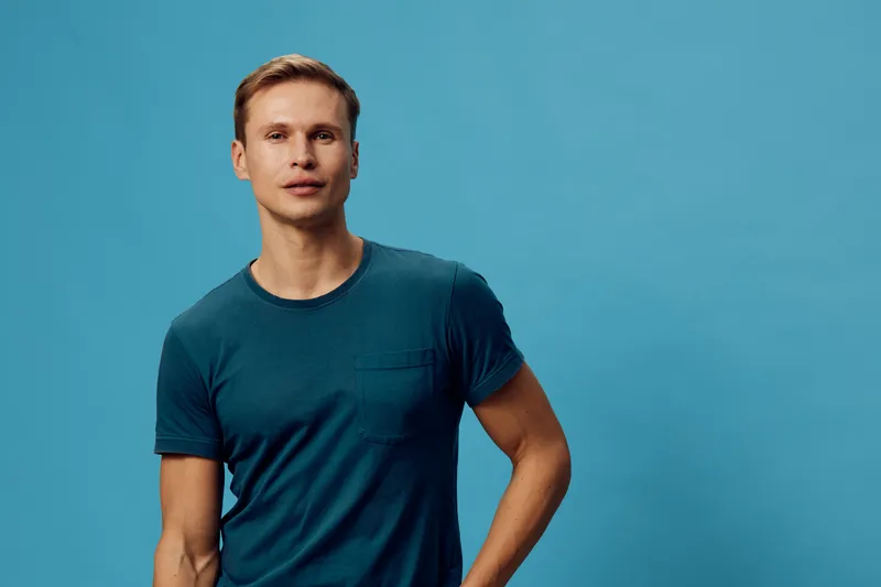 young caucasian man casual blue t-shirt look camera stand over blue background digital nomad work concept
