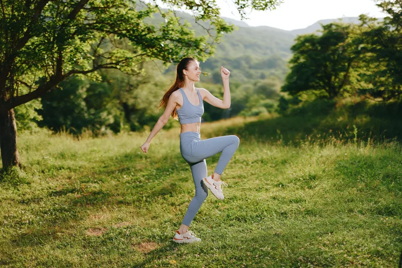Young woman exercising outdoors in blue activewear, depicting motivation, vitality, and a healthy lifestyle in a lush green landscape