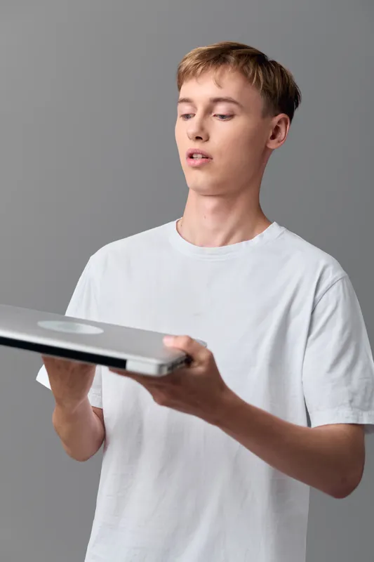 Teen, young man holding a vinyl record for music hobby, casual studio shot, gray backdrop, showcasing interest in tunes and media collection
