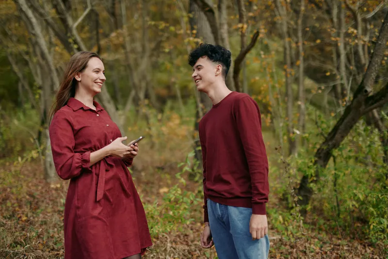 An authentic moment outdoors, a candid smile, natural light, warm autumn tones, and simple wardrobe, portraying a genuine connection and relaxed mood.