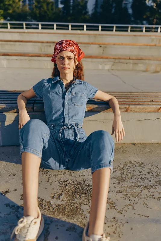 lifestyle woman in modern boho-western denim outfit sitting outdoors, street style, natural light, casual attitude, film color tone enhancing warm mood