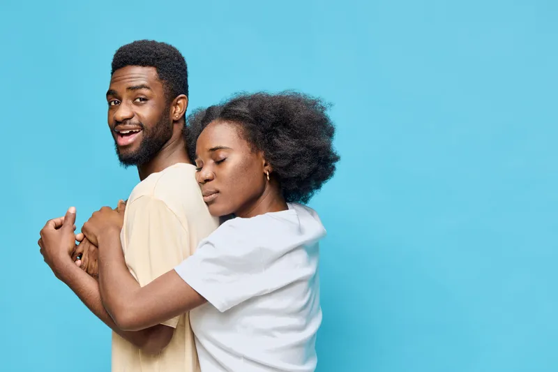 A joyful couple embracing against a vibrant blue background, highlighting love and connection in a stylish casual setting with a focus on emotion and unity