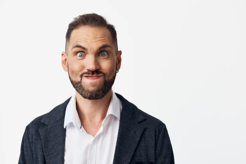 A business professional man with a confident expression stands against an isolated colored background, conveying leadership, focus, and ambition in a corporate setting.