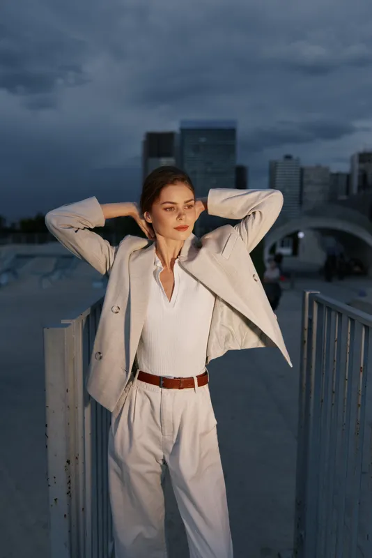 Confident businesswoman in a stylish outfit against a cityscape background, showcasing professionalism and elegance.