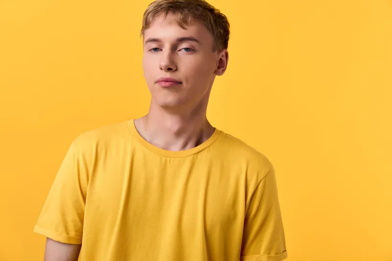Yellow shirted young man stands against a vivid yellow backdrop, projecting casual confidence and modern fashion. Clean lines, relaxed pose, and bold color pairing create a fresh lifestyle look.