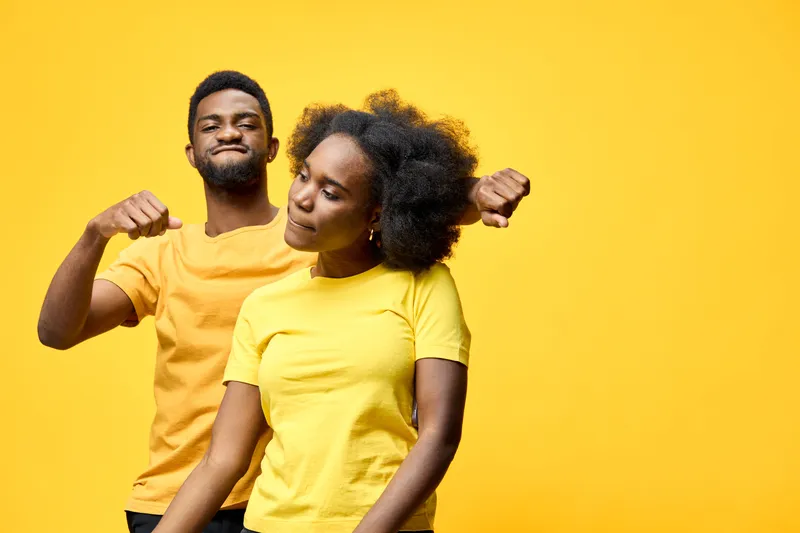 Two models joyfully celebrating their fitness journey in yellow outfits against a vibrant yellow background, showcasing positivity and empowerment
