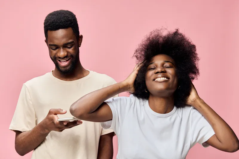 Happy young African couple enjoying time together against a pink background, highlighting joy and connection Perfect for concepts like love, relationship, and happiness