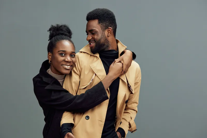Happy couple embracing in stylish clothing, showcasing love and joy against a neutral background, perfect for lifestyle themes of relationships and togetherness