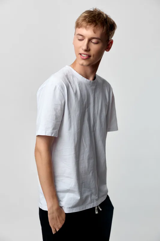 Casual male model wearing a white t shirt in a bright studio, relaxed stance, soft lighting and clean background, ideal for fashion, lifestyle and apparel campaigns