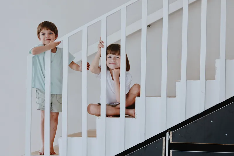 Happy children playing on the stairs, showcasing joy and creativity in a bright indoor space filled with light and warmth, perfect for family-themed projects.