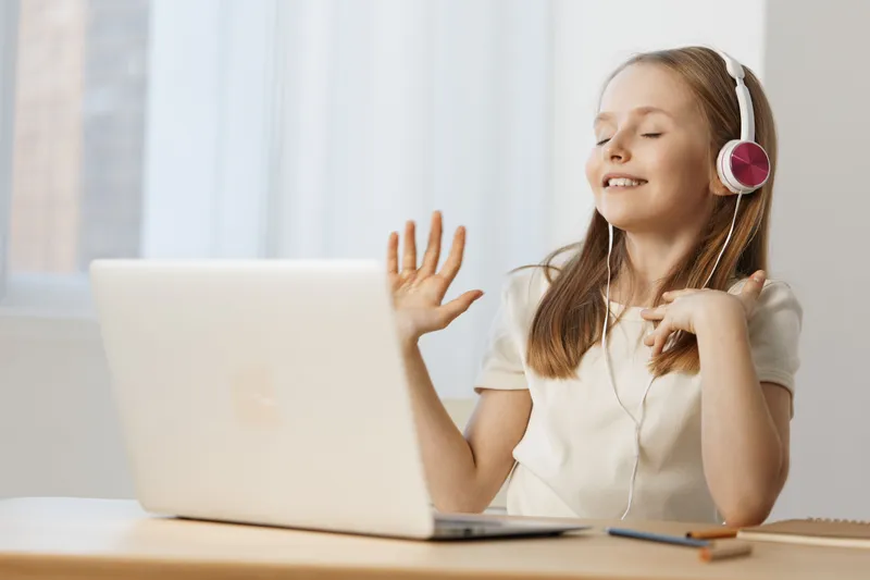 Happy young girl enjoying music while listening on headphones at home, reflecting joy and relaxation in a bright and airy environment