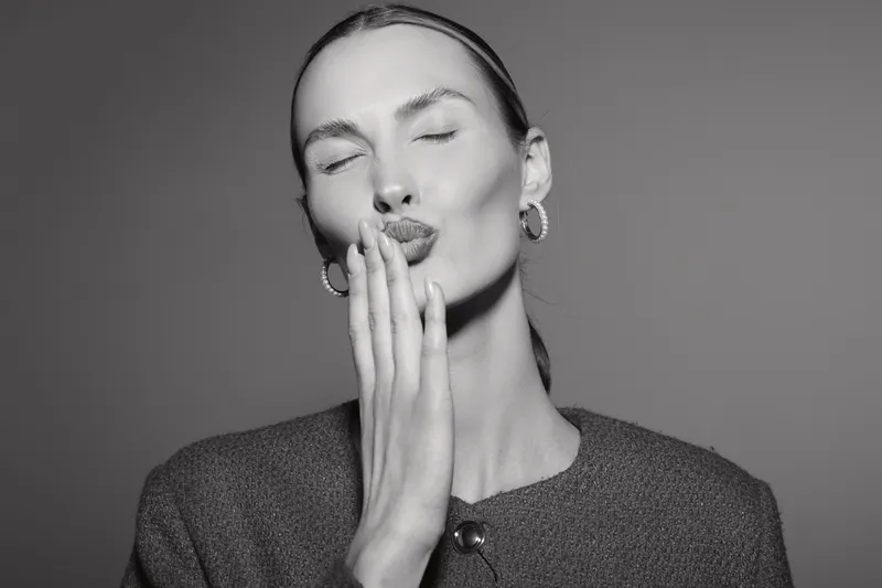 Portrait of a young white woman with light skin blowing a kiss with closed eyes in black and white. Concept for affection, emotion, and femininity in studio lighting.