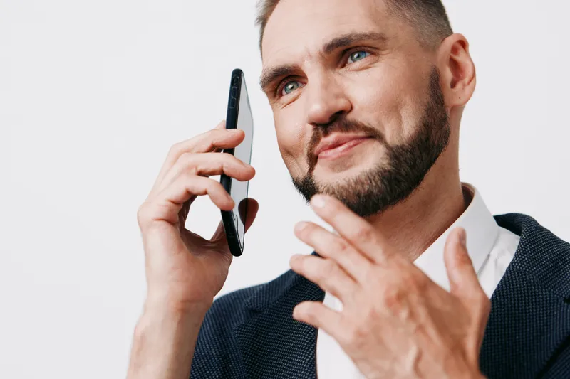 A business professional speaks on a mobile phone against a solid color background, exuding confidence, focus, and calm assurance during a professional conversation.