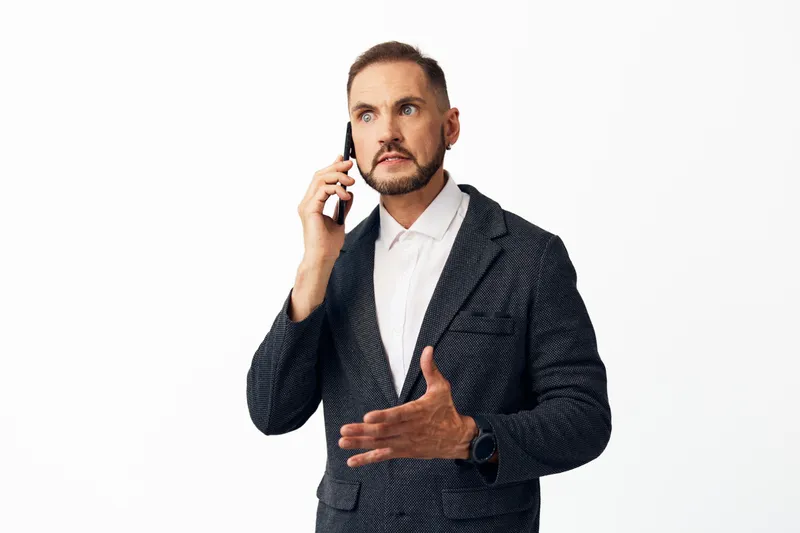 A professional man on a color isolated background speaks on the phone, presenting confidence and urgency, showcasing a strong business mindset and clear communication.