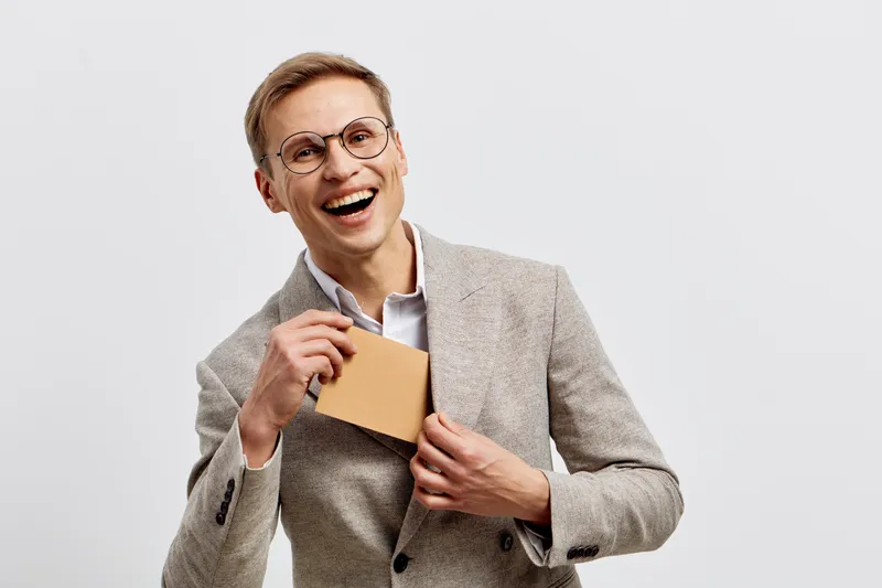 Smiling happy young man wearing glasses holding credit card showing online payment or cryptocurrency transaction concept isolated white background